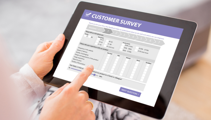 A fingertip touching a tablet with a customer survey displayed
